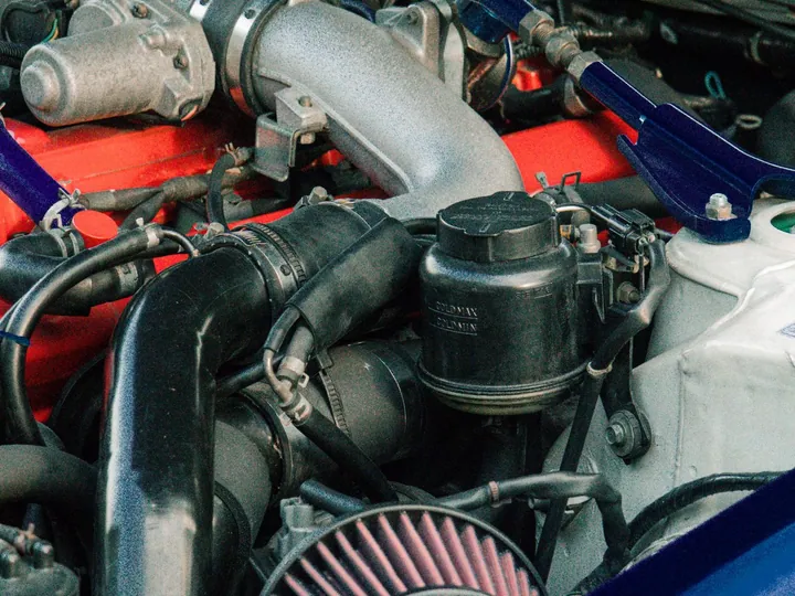 Close view of mechanical components in a car engine bay.