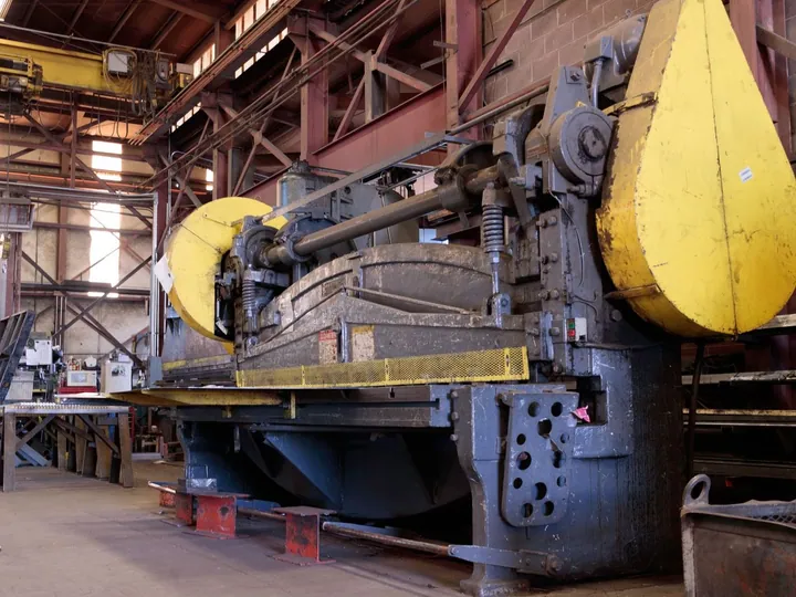 Large industrial machine inside a metalworking workshop.