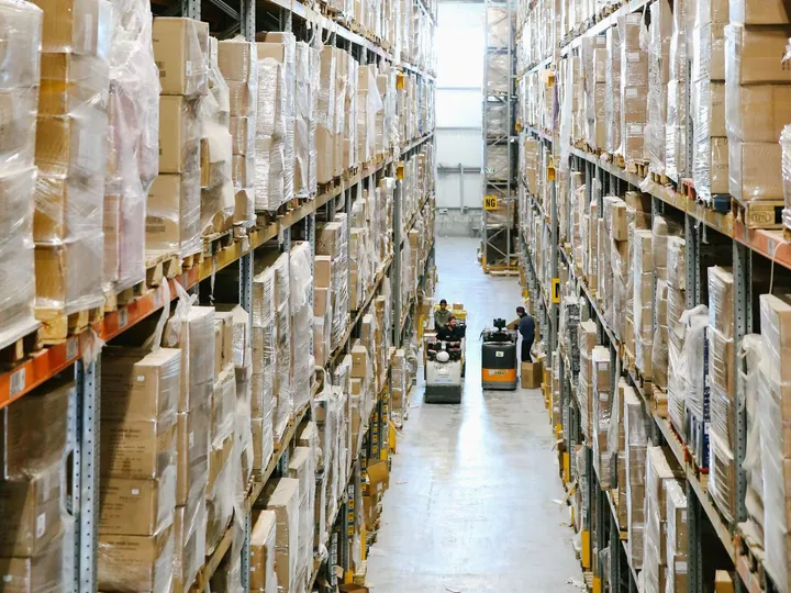 Shelves of wrapped cartons in a warehouse aisle.