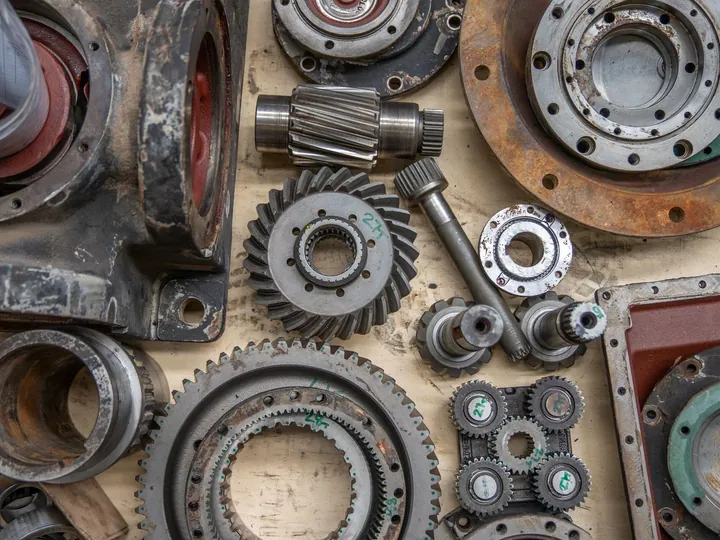 Metal gears, shafts and mechanical parts arranged on a work surface.